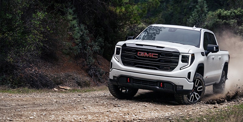 brand new white GMC Sierra 1500 driving up a rocky mountainous road.
