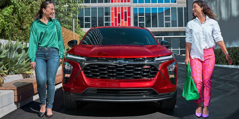Two women smiling and standing in front of 2025 Chevrolet Trax